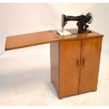 A mid-20th century sewing machine in oak cabinet.
