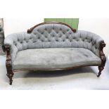 A Victorian mahogany-framed sofa, curved and carved back rail to curved arms,