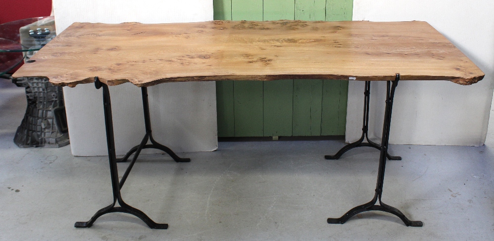 A pine trestle table, redesigned to resemble a section of a tree on black metal supports,