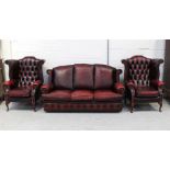 A contemporary three-piece burgundy leather Chesterfield suite comprising a three-seat sofa and two