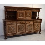 A French oak court cupboard with carved and shaped frieze above two carved cupboard doors flanked