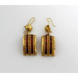 A pair of yellow metal Indian-inspired half-hoop earrings set with red enamel.
