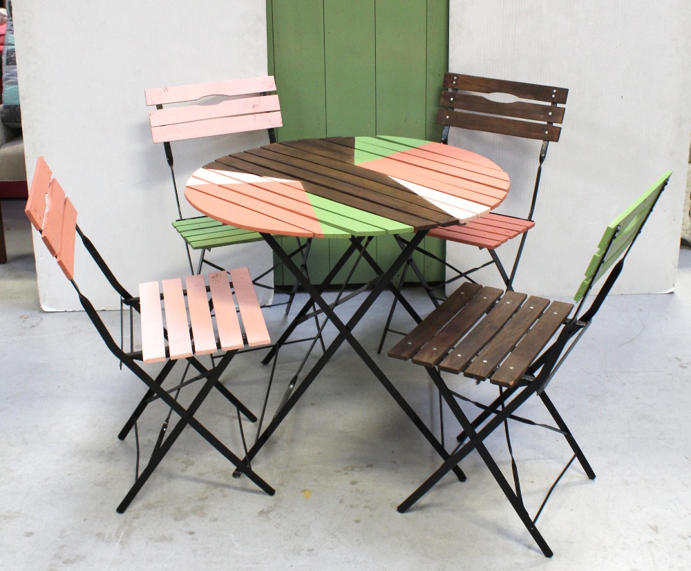 A circular wooden garden table on metal stand and four matching slat garden chairs with metal