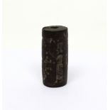 An ancient Near Eastern black limestone cylindrical seal with carved frieze scene depicting a