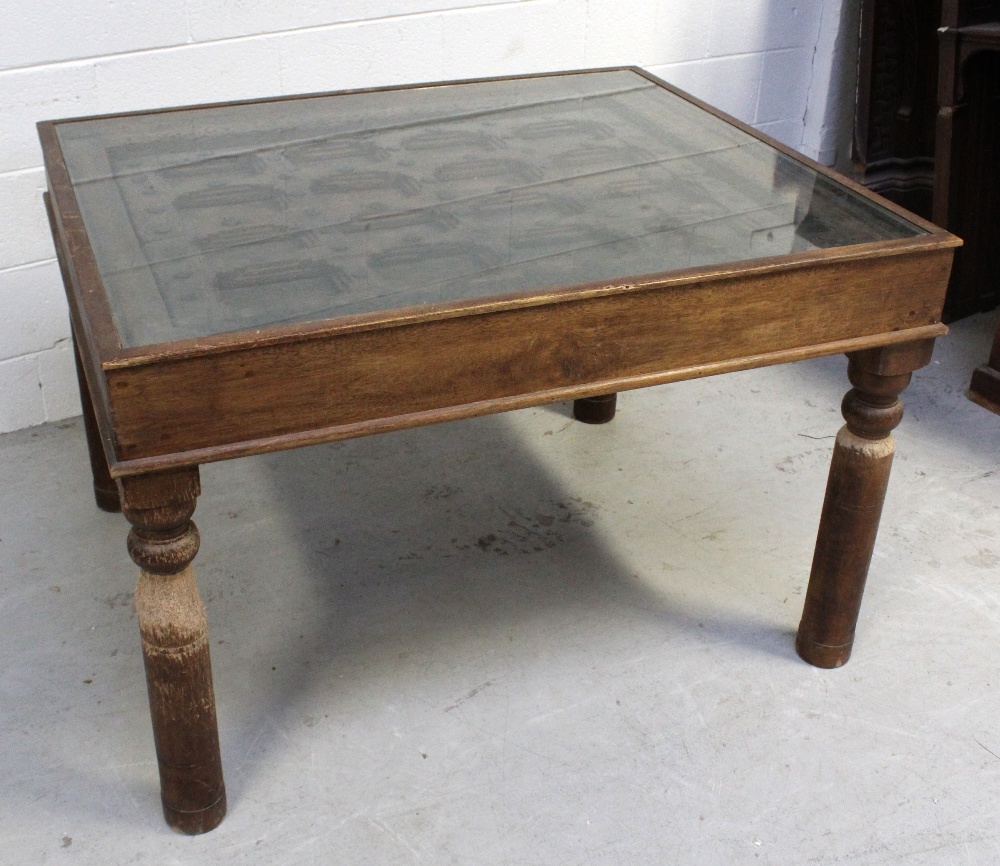 An Indian hardwood table with glass top over an antique window frame insert with metal decoration