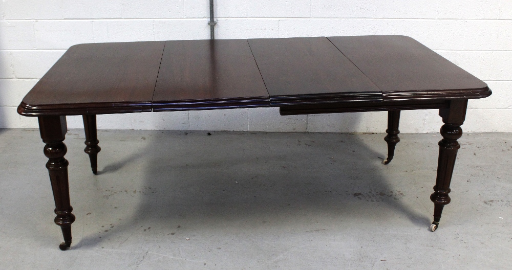 A Victorian mahogany extending dining table with turned fluted supports to castors,