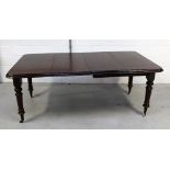 A Victorian mahogany extending dining table with turned fluted supports to castors,