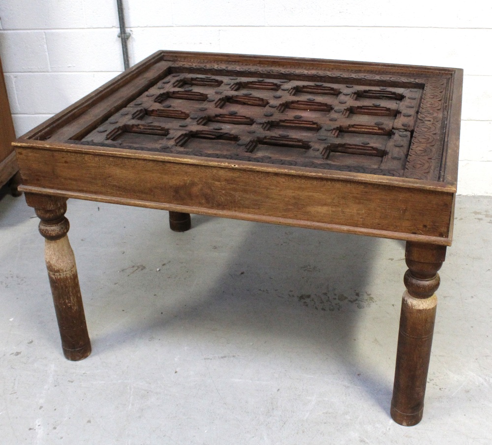 An Indian hardwood table with glass top over an antique window frame insert with metal decoration - Image 2 of 3