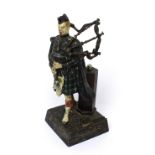 An early 20th century striker/lighter in the form of a Scots bagpiper, height 18cm.