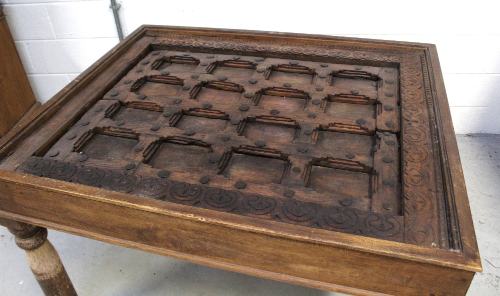 An Indian hardwood table with glass top over an antique window frame insert with metal decoration - Image 3 of 3