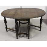 An early 20th century oak drop-leaf dining table on baluster supports and cross-stretchers,