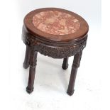 A Chinese hardwood circular stand with carved foliate scrolls above four square section legs with