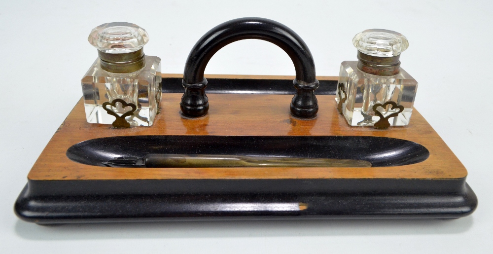 A Victorian walnut inkstand with ebonised detail, two clear glass inkwells and a dip/fountain pen,