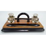 A Victorian walnut inkstand with ebonised detail, two clear glass inkwells and a dip/fountain pen,