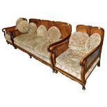 An Edwardian walnut Bergère three-piece suite comprising a three seater settee and a pair of