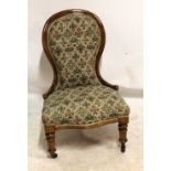 A Victorian mahogany spoon back lady's saloon chair with ring turned front legs on castors.