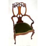An Edwardian mahogany and inlaid open elbow chair with carved foliate scroll motifs to the back,