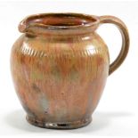 WILLIAM FISHLEY HOLLAND (1889-1969); a red earthenware jug covered in streaky glossy treacle glaze,