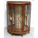 A c1940s mahogany bow-front display cabinet with two interior glass shelves to squat cabriole