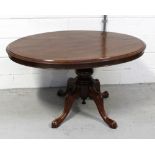 A Victorian mahogany oval loo table with turned baluster column above quadripartite scrolling