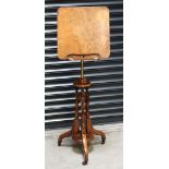 A Victorian walnut music stand with brass central column, on three outswept legs to castors,