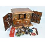 An oak smokers' cabinet, the hinged doors and lid enclosing an octagonal tobacco jar decorated