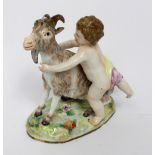 A 19th century German porcelain figure group of a putti attempting to ride a goat (af), height 15.