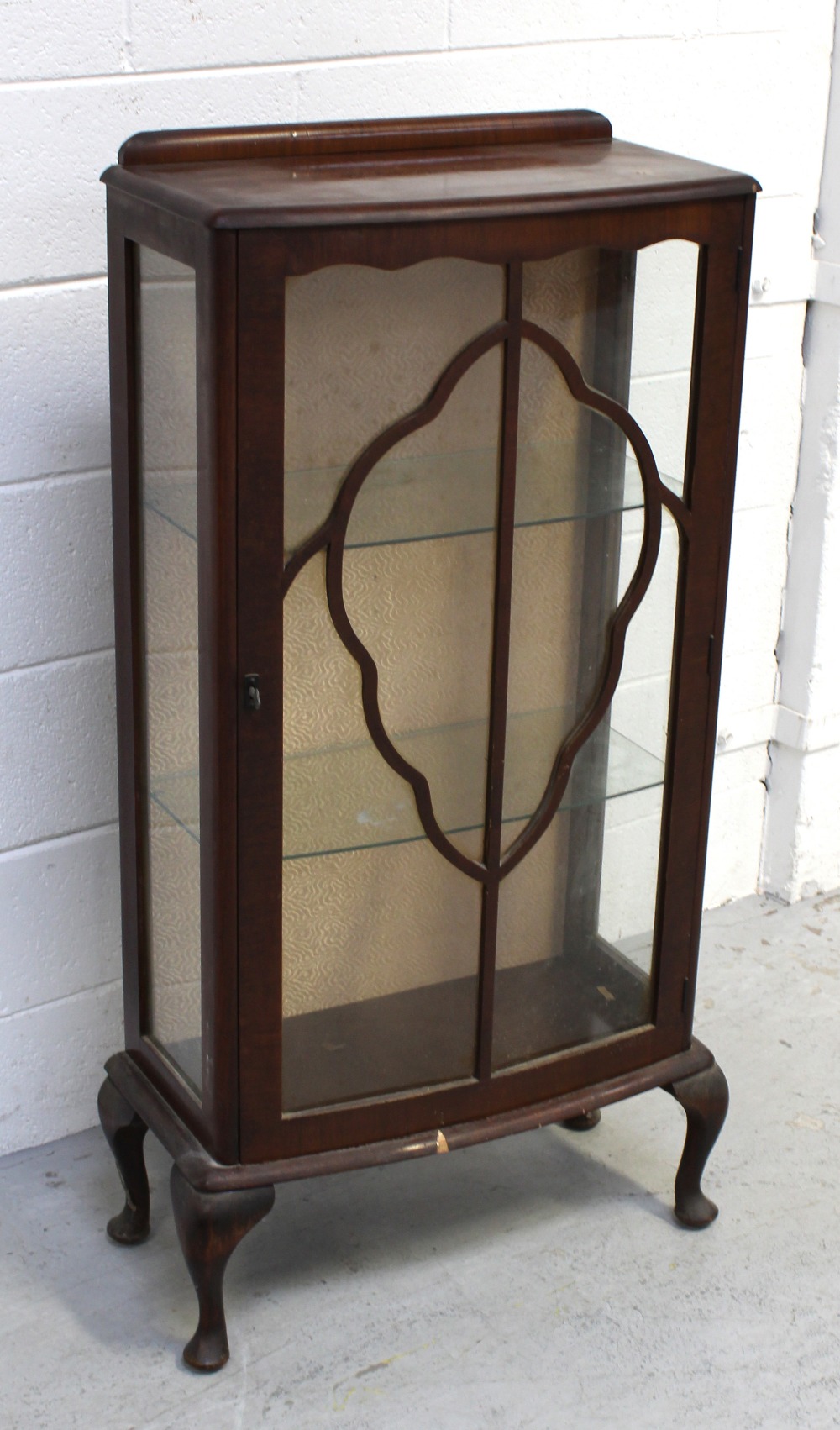 A 1940s walnut display cabinet with cartouche-shaped glazing bars to the door enclosing two glass