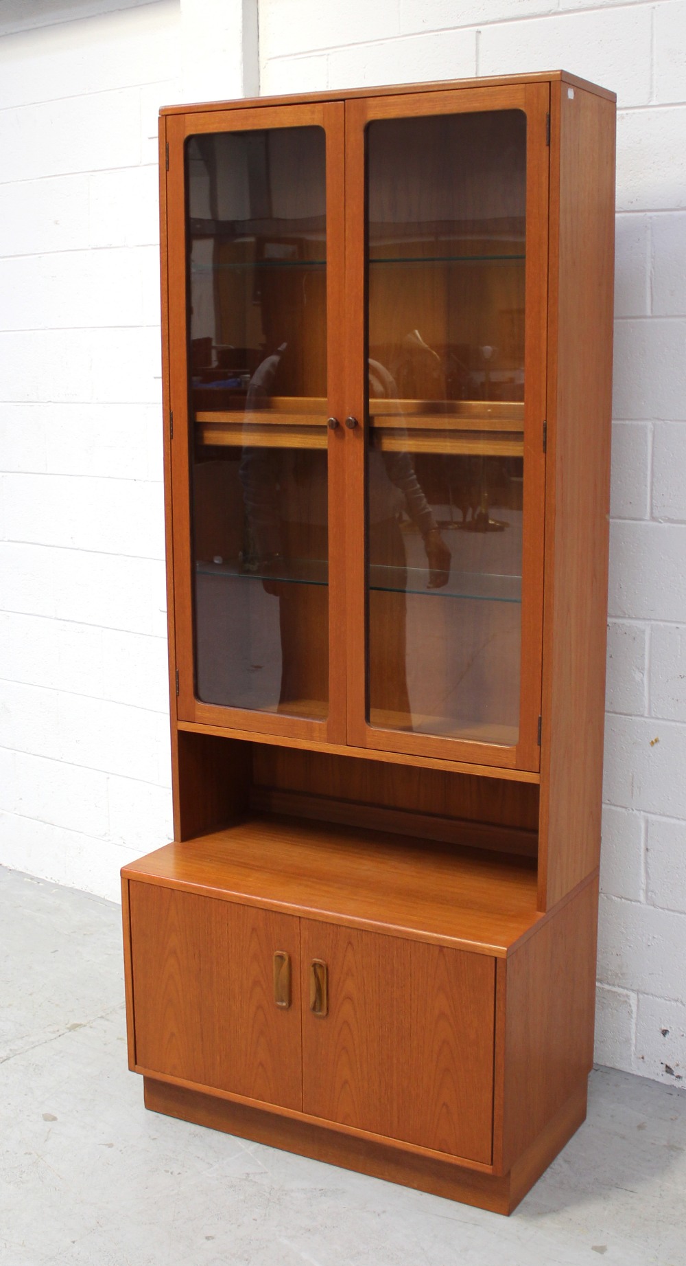 A G-Plan teak cabinet/bookcase with twin glazed doors enclosing three shelves; two glass,