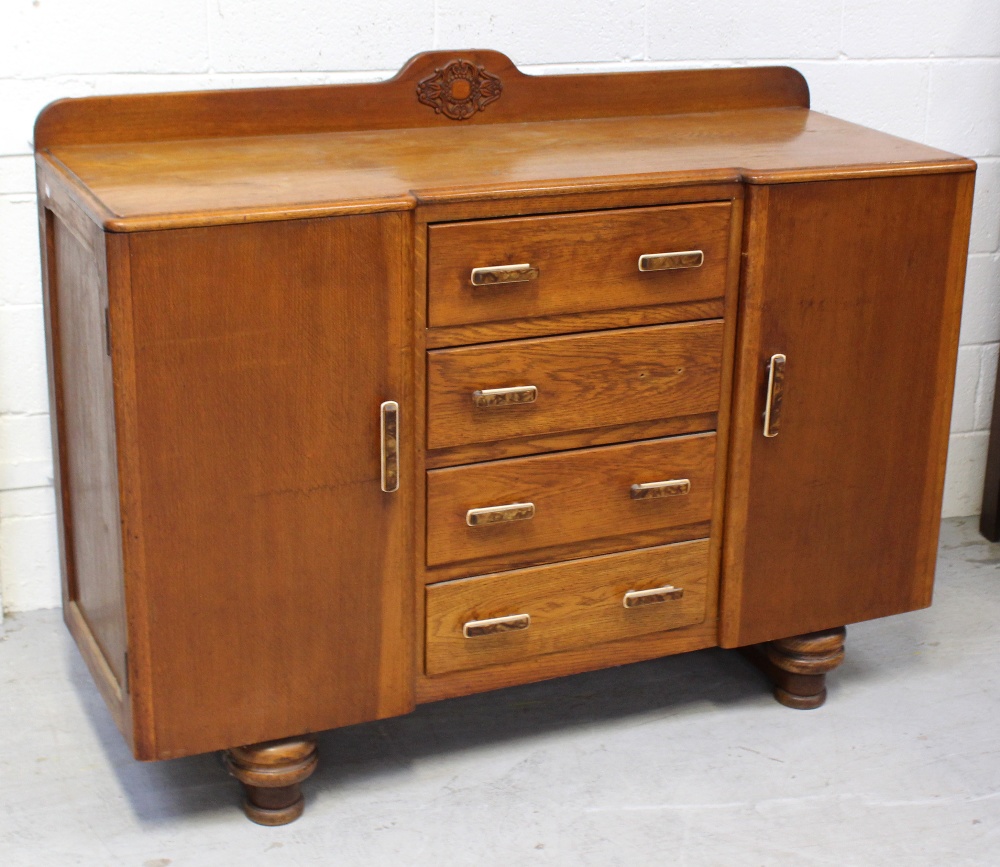 A 1950s oak sideboard/cabinet, central bank of four drawers flanked by cupboards,