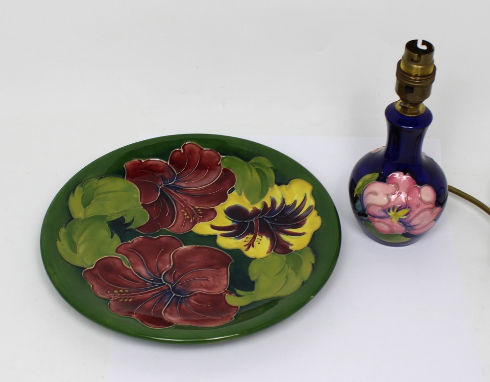 A Moorcroft 'Hibiscus' pattern tube line decorated green ground plate with 'WM' monogram,