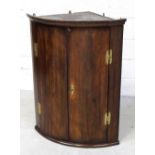 A George III mahogany bow-front corner cupboard with brass 'H' hinges and escutcheon, height 97.5cm.