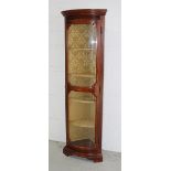 A 20th century mahogany glazed corner unit with four interior shelves with damask fabric covering,