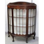 An Edwardian mahogany bow-front display cabinet with arched decoration to the glass central door