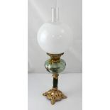 A brass oil lamp with floral-decorated font and white globe, height 59cm.