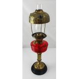 A Victorian brass oil lamp with red glass font and coloured glass encrusted shade, height 64cm.