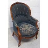 A Victorian walnut nursing chair with blue floral tapestry upholstery, curved support and castors.