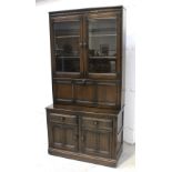 An Ercol oak 'Colonial' bookcase cabinet, two gazed doors over drop-down cocktail cabinet,