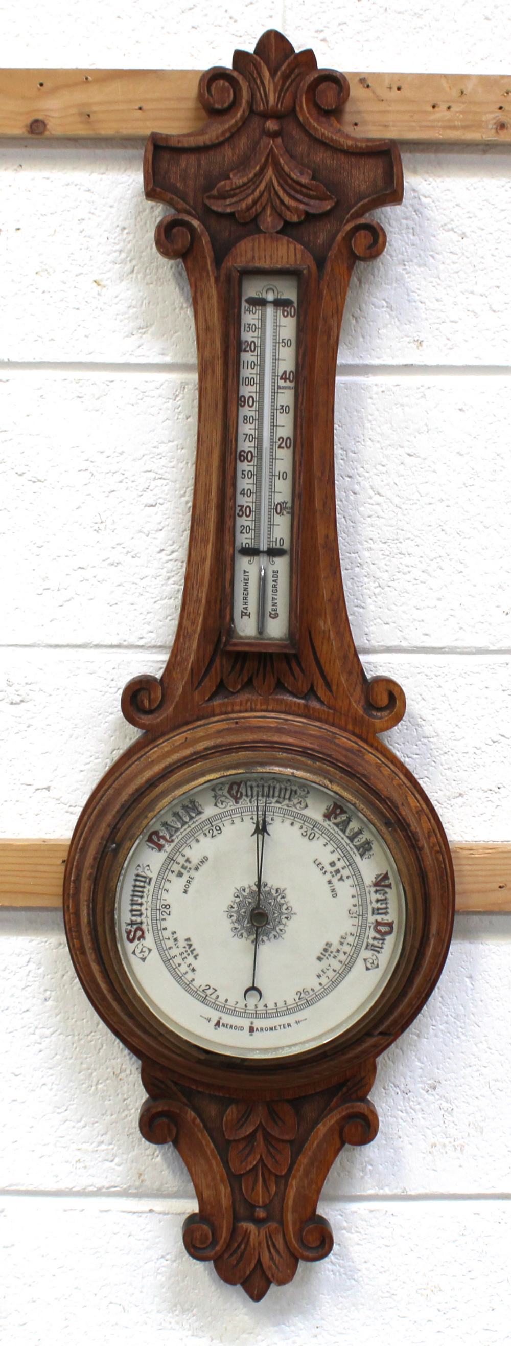 An early 20th century oak aneroid barometer and thermometer, length 88cm.