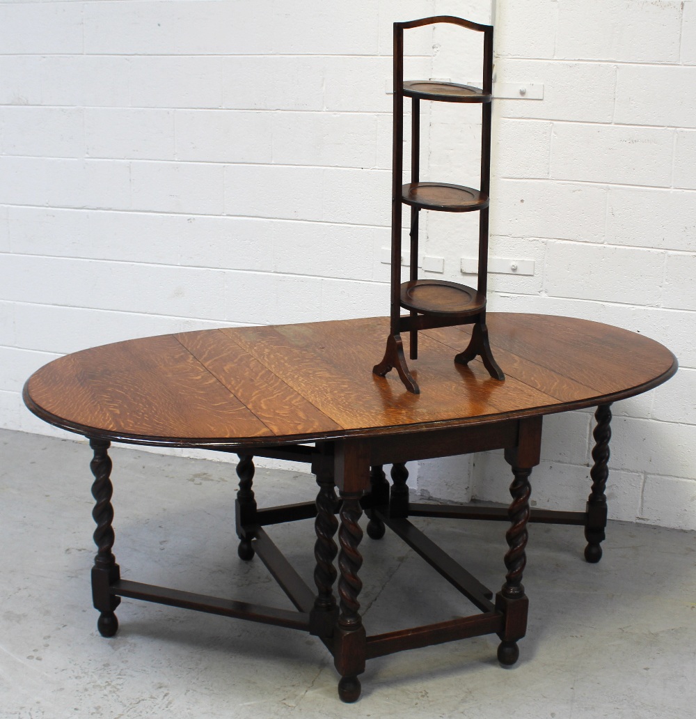 A mid-20th century oak oval draw-leaf gate-leg dining table on wrythen turned supports and cross