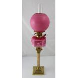 A brass and marble-effect oil lamp with pink swan decorated font and embossed globe, height 82cm.