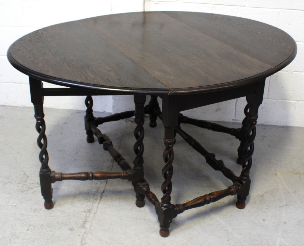 An early-to-mid 20th century oak gate-leg dining table on wrythen supports and turned cross