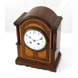 An Edwardian mahogany and inlaid eight-day mantel clock with domed top above white enamel dial set