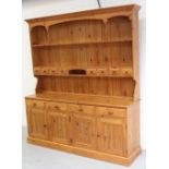 A bespoke pine Welsh dresser, two plate racks over four frieze drawers, over four cupboard doors,