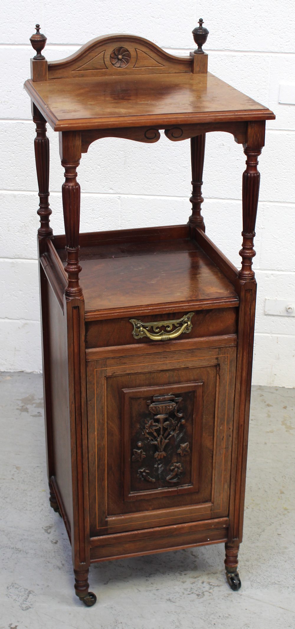 An Edwardian rosewood Arts and Crafts coal bin with carved central door above turned supports to