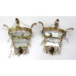 A pair of gilt metal foliate scroll decorated wall lights with cut glass drops,