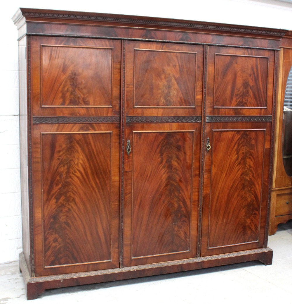 An early 20th century mahogany three-door wardrobe fitted with drawers and hanging space,