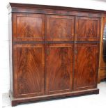 An early 20th century mahogany three-door wardrobe fitted with drawers and hanging space,