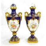 A pair of Coalport twin handled urns painted with floral panels on gilt blue ground, no.