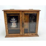 An oak tabletop cabinet housing two clear glass decanters, ceramic jar and two dishes,